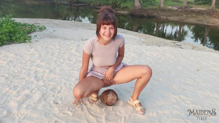A shy lady squirts a small trickle of pee on a coconut